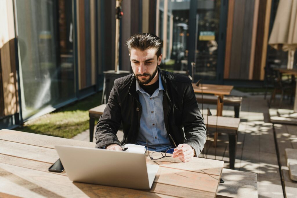 Man working on laptop outdoors, representing building an online business before retirement.